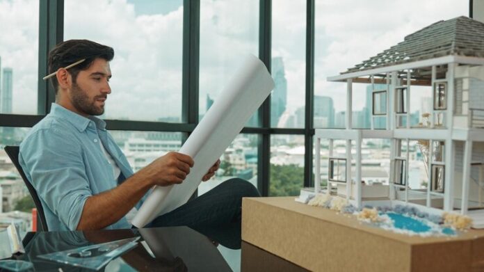 smiling-engineer-looking-project-plan-while-design-house-model-tracery_31965-477508